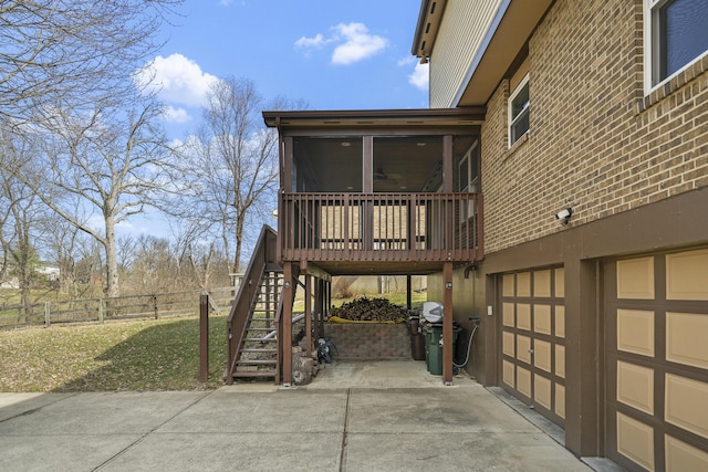 view of property exterior featuring fence, stairway, a yard, a sunroom, and driveway