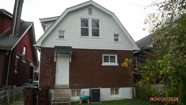 rear view of house featuring fence, a gambrel roof, entry steps, central air condition unit, and brick siding