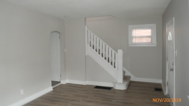 foyer with stairs, visible vents, wood finished floors, and baseboards