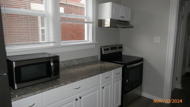 kitchen with a healthy amount of sunlight, appliances with stainless steel finishes, white cabinets, and extractor fan