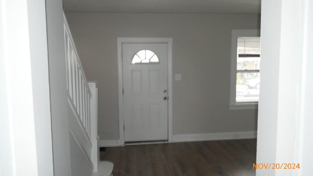 foyer entrance with baseboards, stairs, and dark wood-type flooring