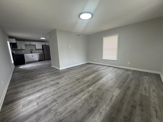 unfurnished living room featuring baseboards, dark wood-style flooring, visible vents, and a sink