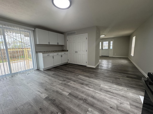 kitchen featuring baseboards, visible vents, white cabinetry, open floor plan, and dark wood-type flooring