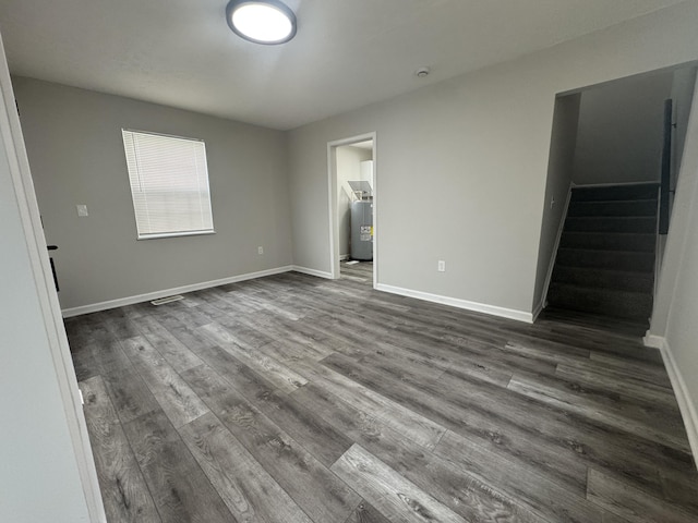 unfurnished bedroom featuring water heater, baseboards, and dark wood-style floors