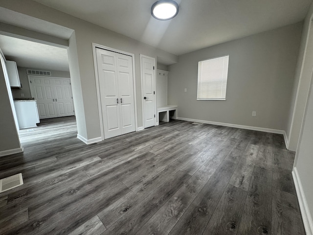 unfurnished bedroom featuring baseboards, dark wood-style flooring, a closet, and visible vents