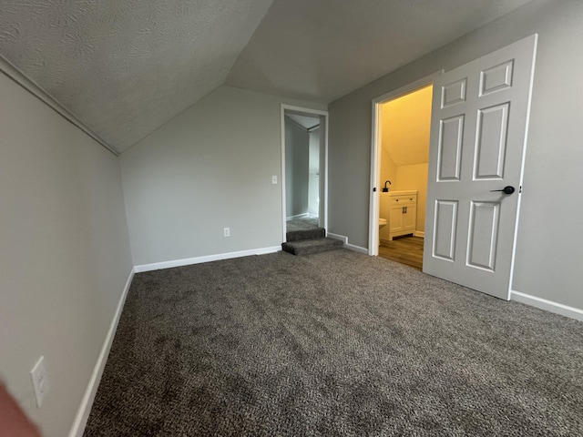 additional living space with vaulted ceiling, baseboards, and dark carpet