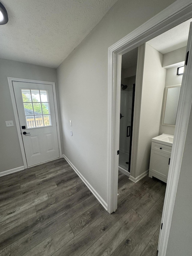 doorway to outside featuring baseboards, dark wood-style flooring, and a textured ceiling
