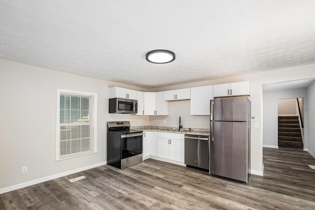 29 Race St, Dry Ridge, KY 41035 - kitchen with stainless steel appliances, dark wood-style flooring, white cabinets, a textured ceiling, and light stone countertops