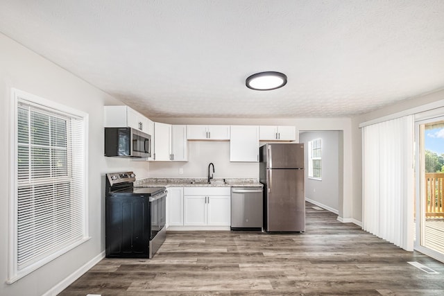 29 Race St, Dry Ridge, KY 41035 - kitchen with appliances with stainless steel finishes, white cabinets, wood finished floors, and light stone countertops