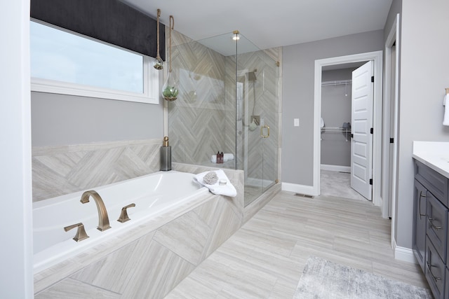 full bath with visible vents, a stall shower, vanity, a bath, and a spacious closet