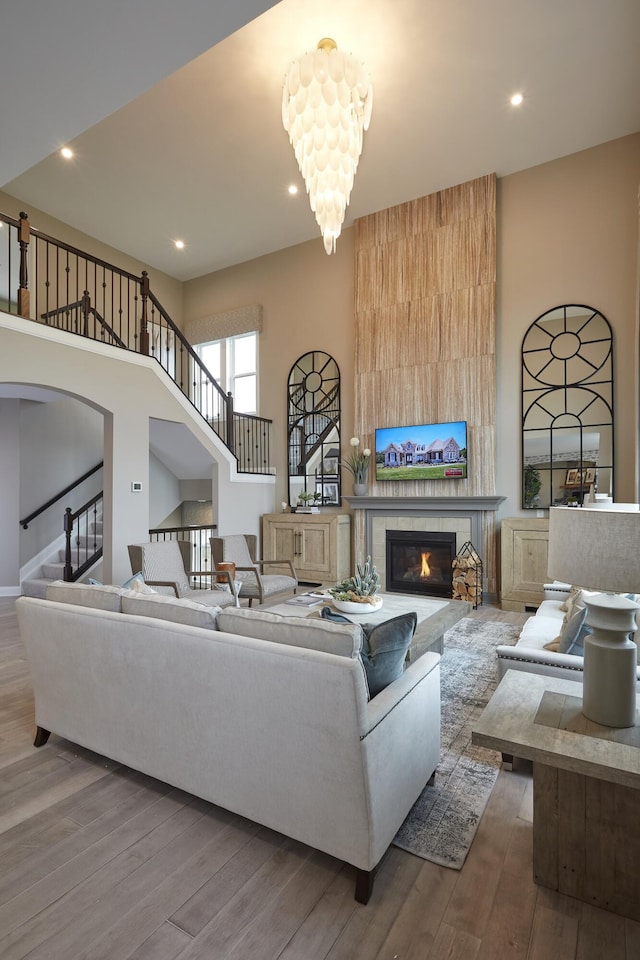 living area featuring stairway, wood finished floors, a fireplace, and a chandelier