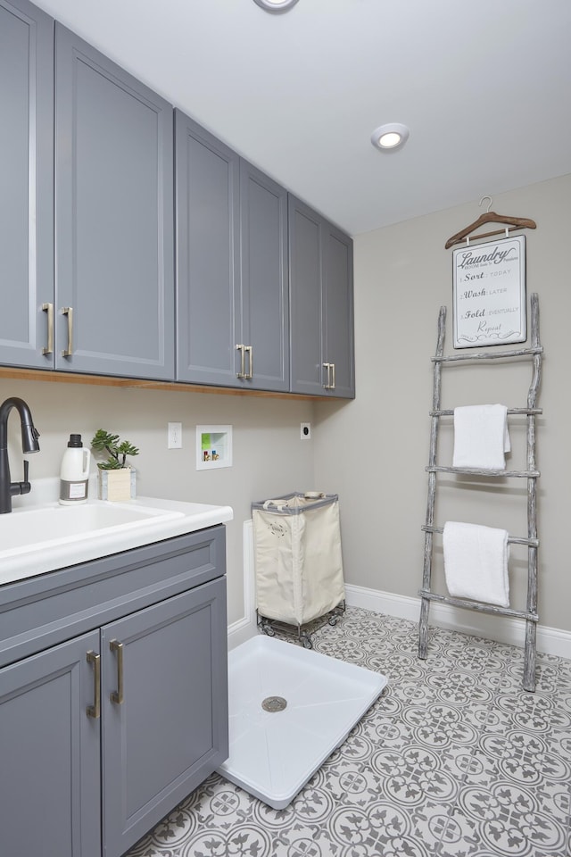 laundry room featuring washer hookup, a sink, cabinet space, light tile patterned flooring, and baseboards