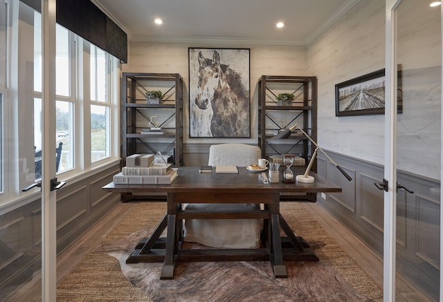 home office featuring crown molding, a decorative wall, wood finished floors, and wainscoting