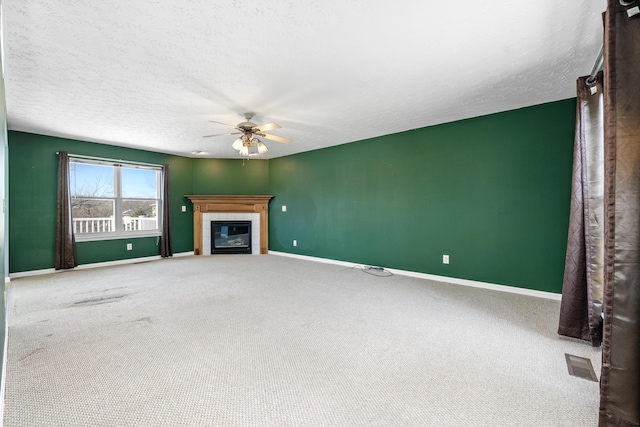 unfurnished living room featuring visible vents, baseboards, ceiling fan, and a tiled fireplace