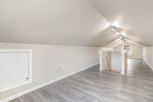 additional living space with baseboards, lofted ceiling, and wood finished floors