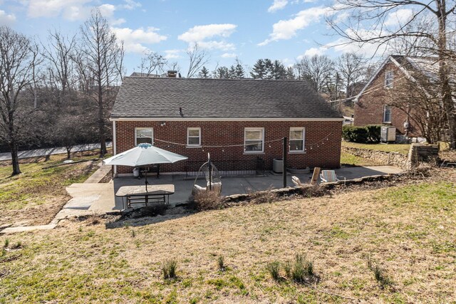 back of house featuring a yard, a patio area, brick siding, and a shingled roof