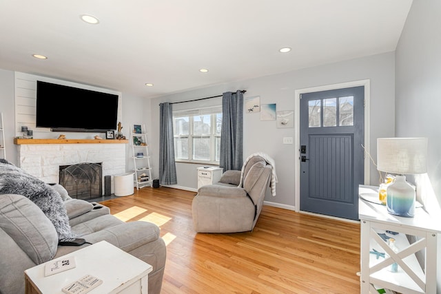 living area featuring recessed lighting, light wood-type flooring, baseboards, and a fireplace