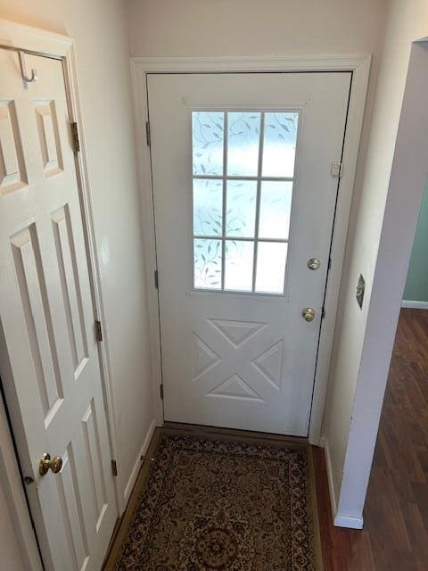 doorway to outside featuring baseboards and wood finished floors