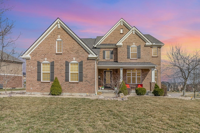 traditional home featuring brick siding, a porch, and a front lawn