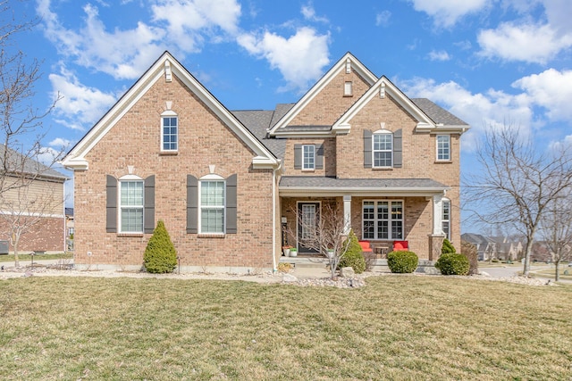 traditional-style house featuring brick siding, covered porch, and a front lawn