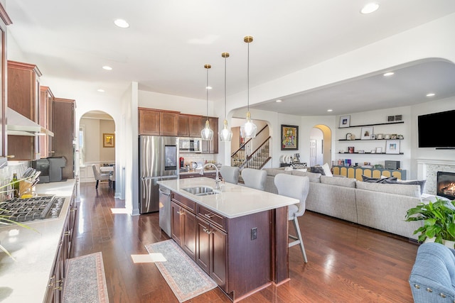 kitchen featuring a sink, arched walkways, appliances with stainless steel finishes, and open floor plan