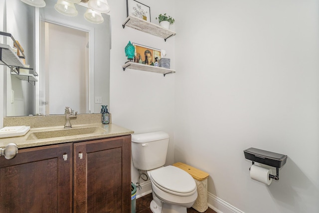 bathroom with toilet, vanity, and baseboards