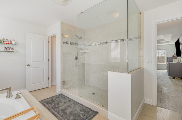 bathroom with tile patterned floors, a bathing tub, a stall shower, and baseboards