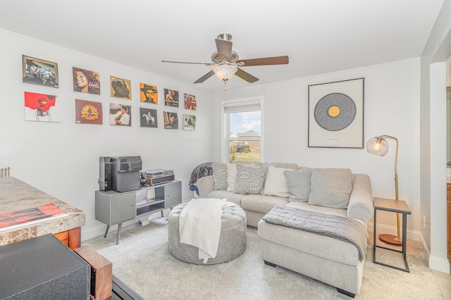 living area with baseboards and ceiling fan