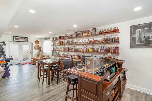 bar featuring recessed lighting, a bar, light wood-type flooring, and baseboards