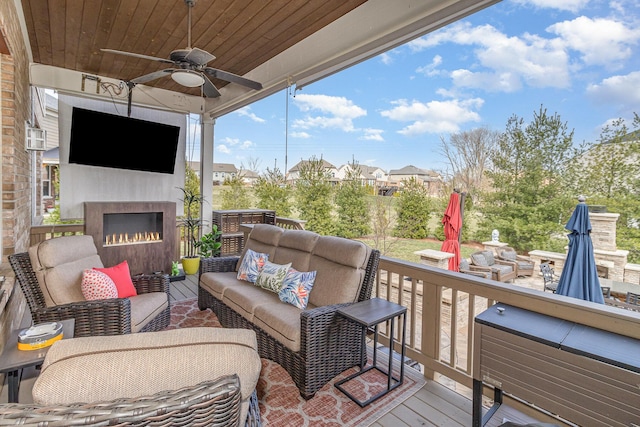 deck with an outdoor living space with a fireplace and a ceiling fan