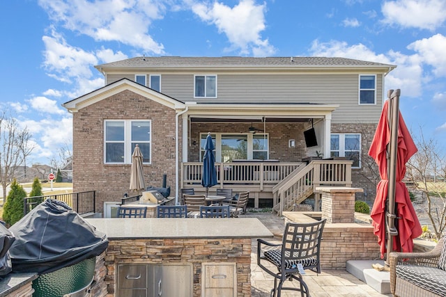 back of property featuring a patio area, brick siding, outdoor dry bar, and an outdoor kitchen