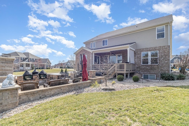 rear view of house with a yard, brick siding, a wooden deck, and a patio area