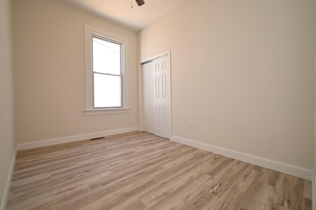 unfurnished room featuring visible vents, light wood-style flooring, a ceiling fan, and baseboards