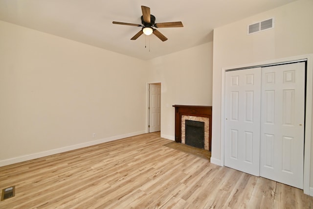 unfurnished living room with visible vents, baseboards, a stone fireplace, and light wood finished floors