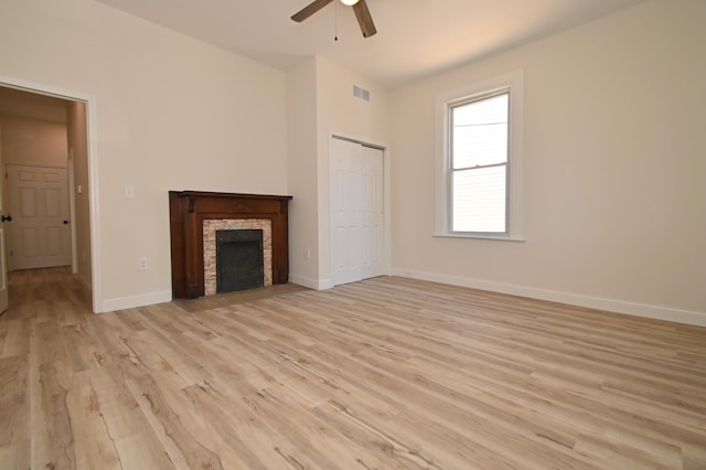 unfurnished living room featuring a ceiling fan, visible vents, light wood finished floors, baseboards, and a fireplace