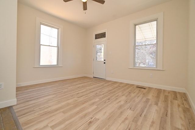 interior space featuring light wood-type flooring, visible vents, baseboards, and ceiling fan