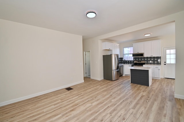 kitchen featuring visible vents, backsplash, stainless steel appliances, white cabinets, and light wood finished floors