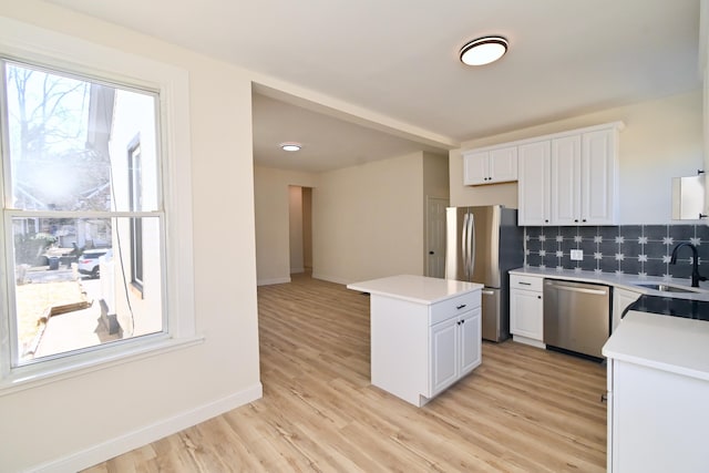 kitchen featuring a sink, a kitchen island, white cabinetry, appliances with stainless steel finishes, and light countertops