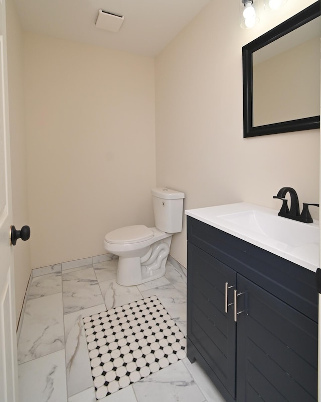 bathroom featuring toilet, marble finish floor, and vanity