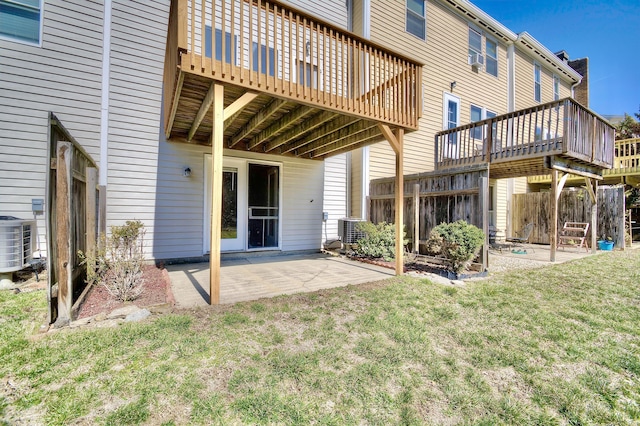 back of property with a wooden deck, a patio, a lawn, and central AC unit