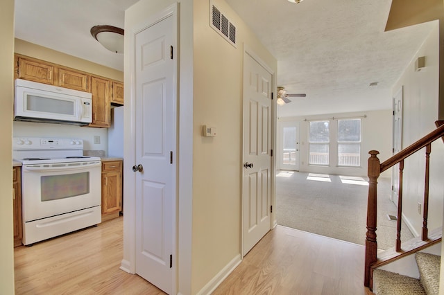 kitchen with visible vents, baseboards, open floor plan, light wood-style floors, and white appliances