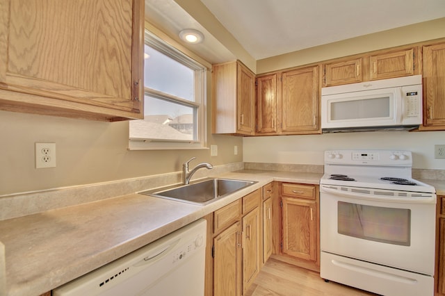 kitchen featuring light wood finished floors, white appliances, light countertops, and a sink