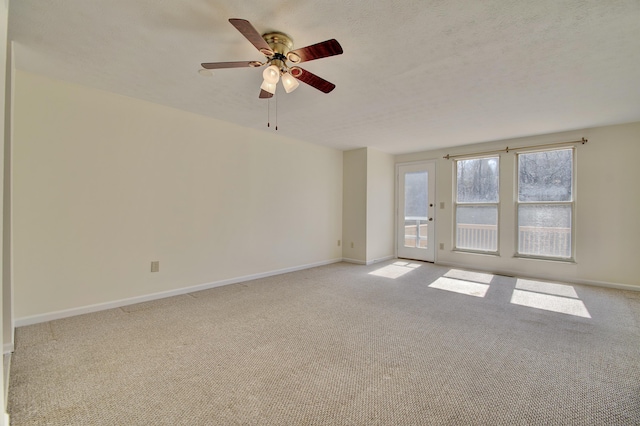 spare room with baseboards, light colored carpet, a ceiling fan, and a textured ceiling