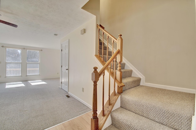 stairs featuring baseboards, visible vents, a textured ceiling, and carpet