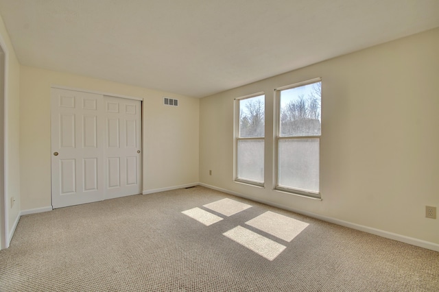 unfurnished bedroom with visible vents, baseboards, carpet, and a closet