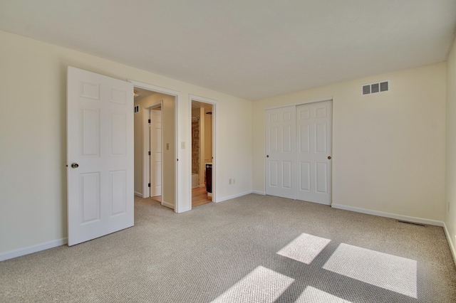 unfurnished bedroom with baseboards, visible vents, carpet floors, a closet, and ensuite bathroom