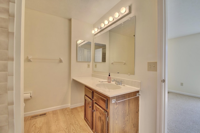 bathroom with vanity, wood finished floors, visible vents, and baseboards