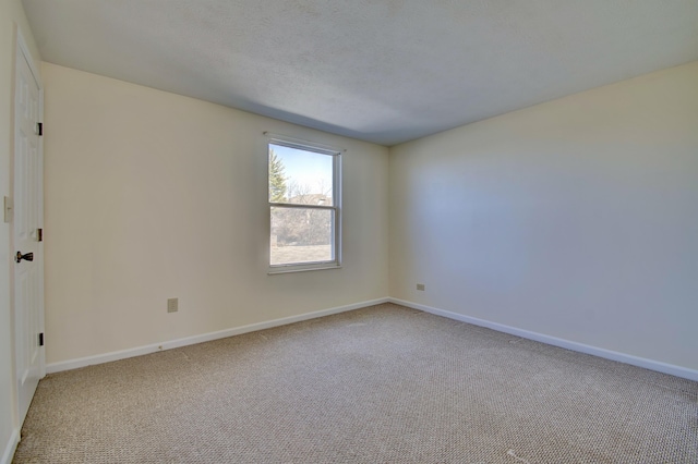 empty room featuring a textured ceiling, baseboards, and carpet