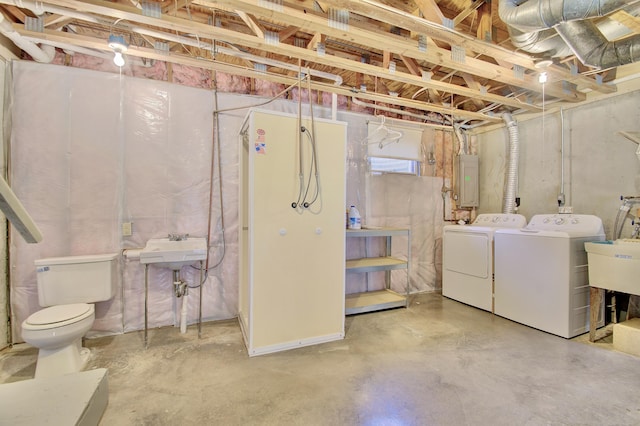 unfinished below grade area with a sink, electric panel, and washing machine and clothes dryer