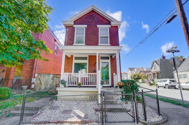 traditional-style home with a fenced front yard, brick siding, covered porch, and a gate